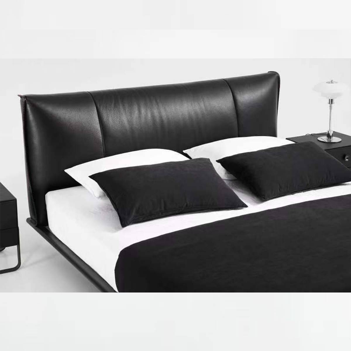 Bed made up with white sheets and black pillows showing the headboard design