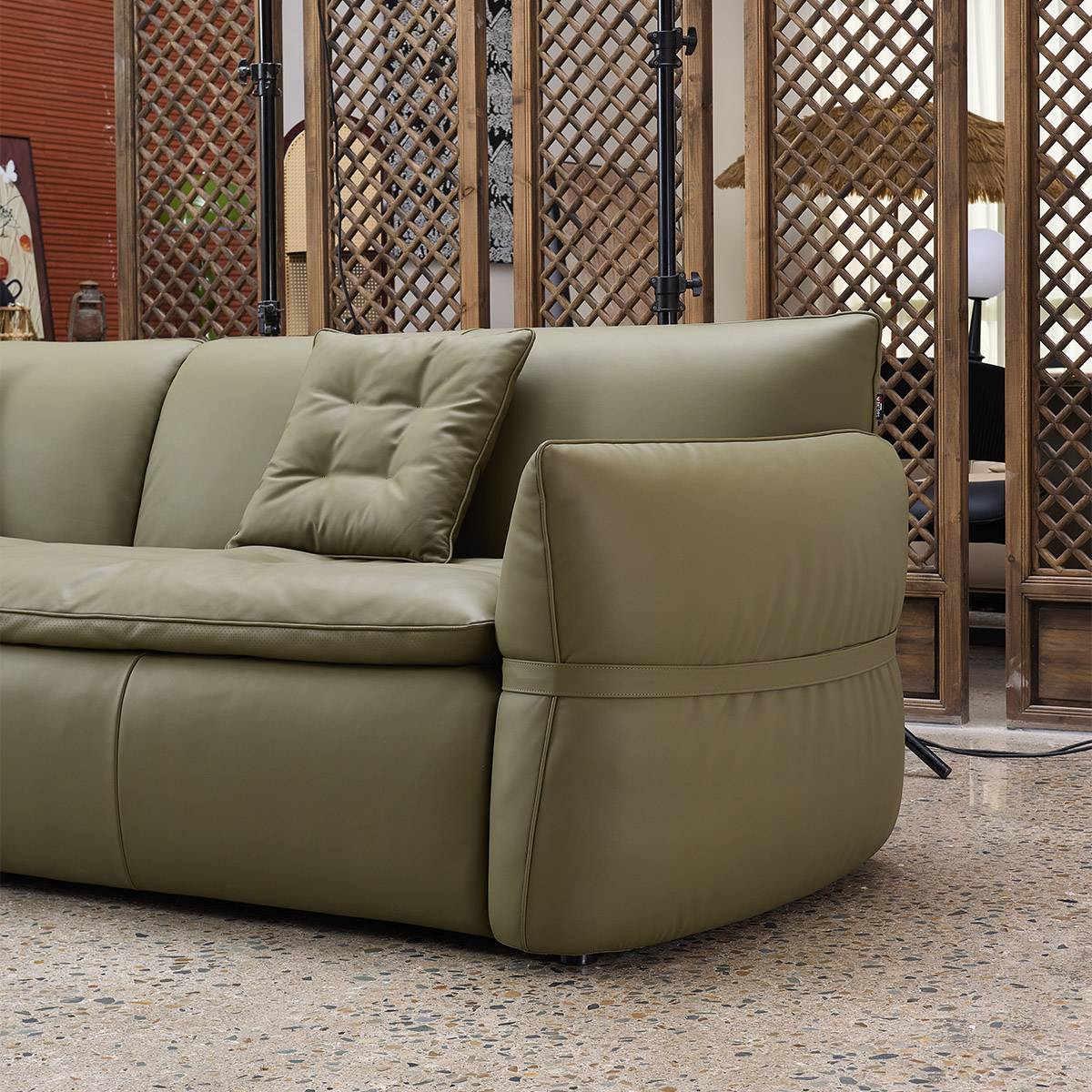 Side profile view of the olive green leather sofa showing the armrest detail and five-point legs