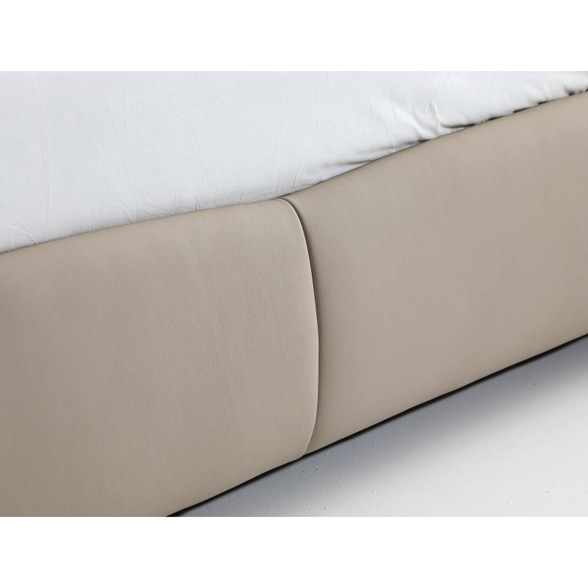 Side view of the beige leather bed frame base with white bedding