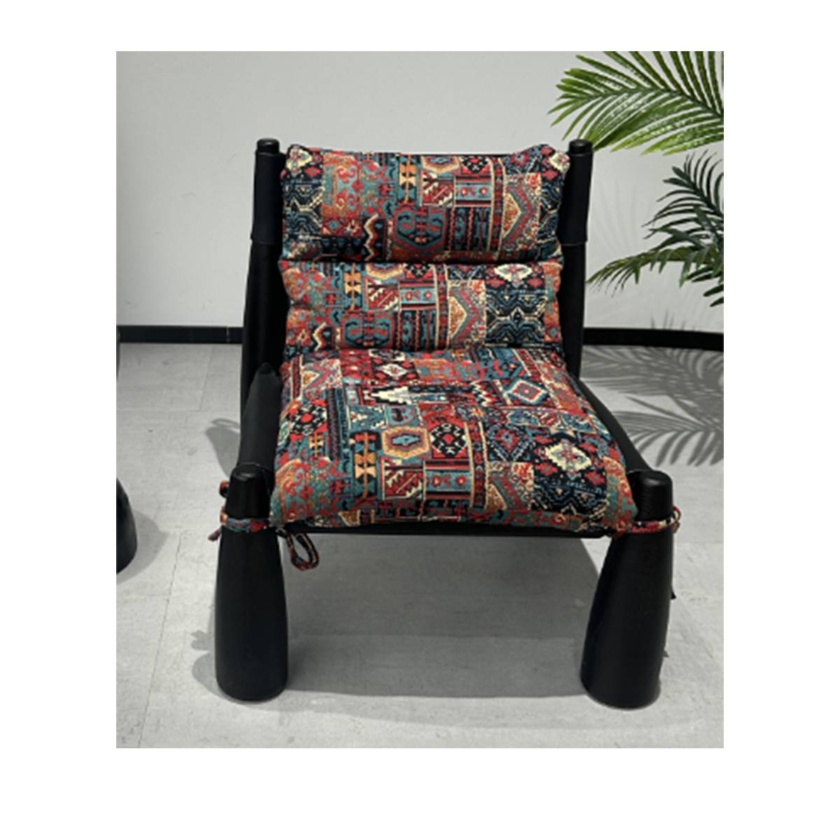 Front view of a black wooden lounge chair with elephant-leg style supports and colorful patchwork cushions.