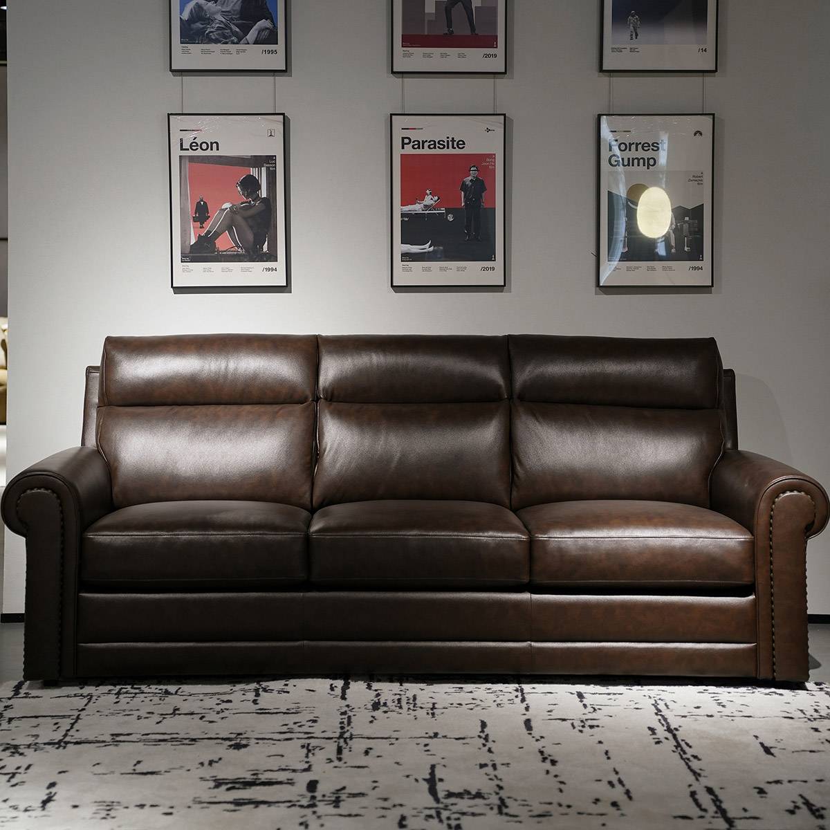 Lourdes sofa displayed in a showroom with movie posters on the wall