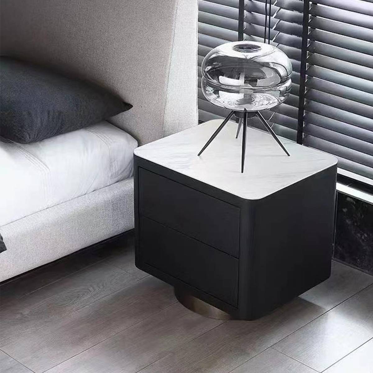 Bedside table placed next to a bed with a spherical lamp