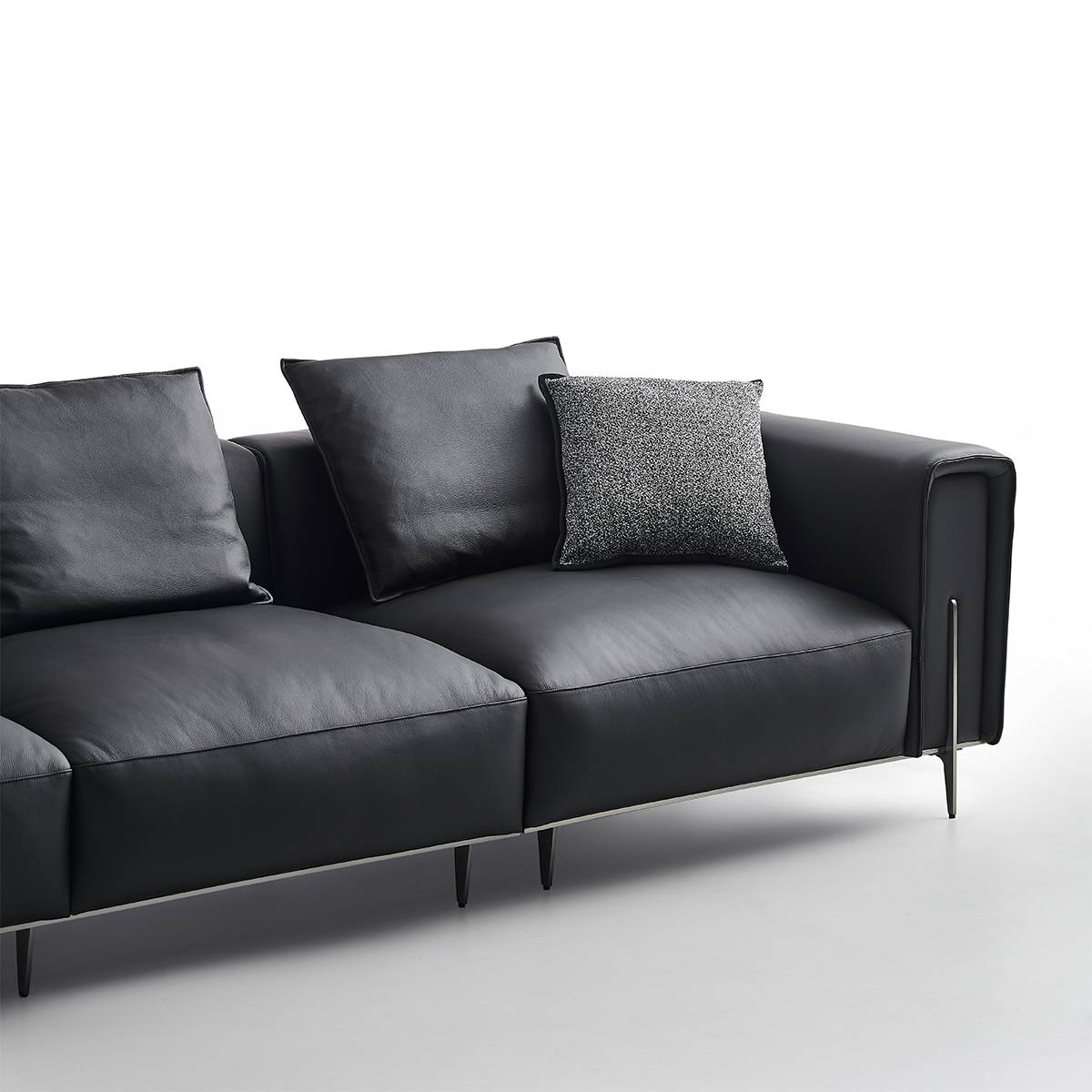Angled view of the black leather sofa with decorative pillows