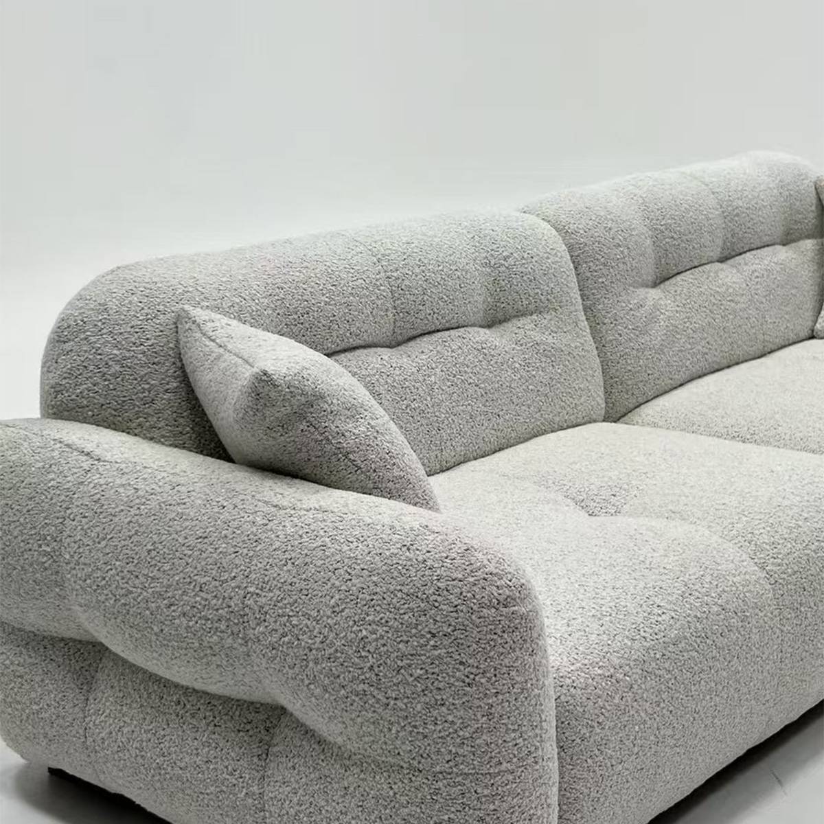 Close-up detail of the bouclé fabric texture and tufted cushioning