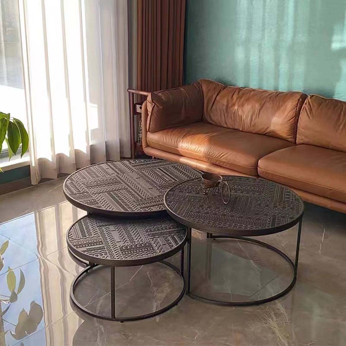 Nesting coffee tables placed in front of a brown leather sofa