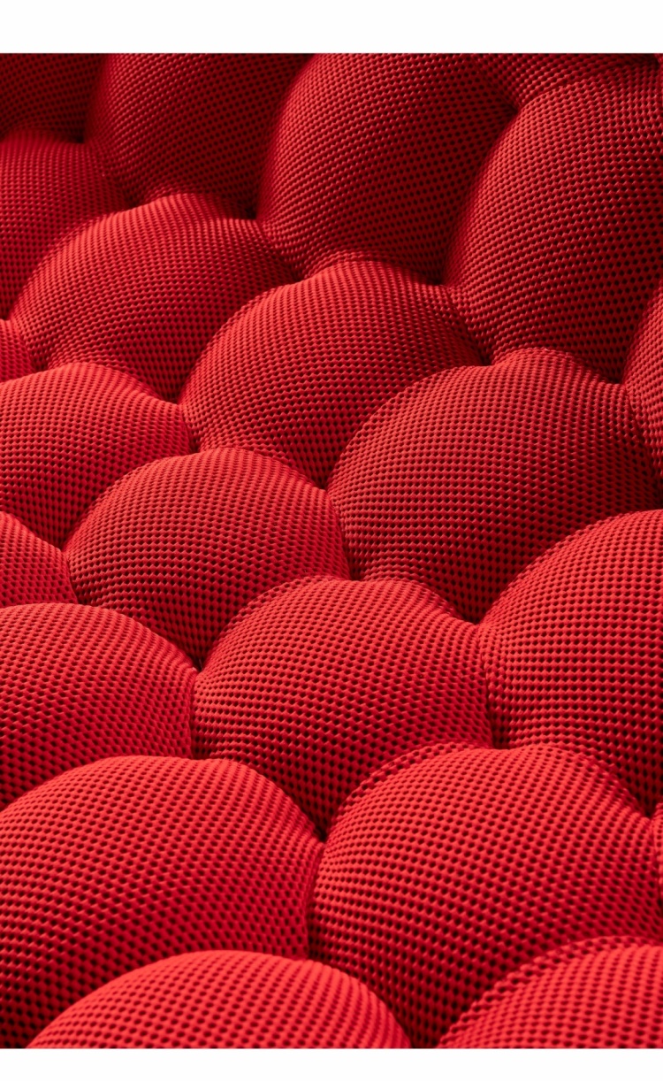 Extreme close-up of the red textured fabric and bubble stitching.