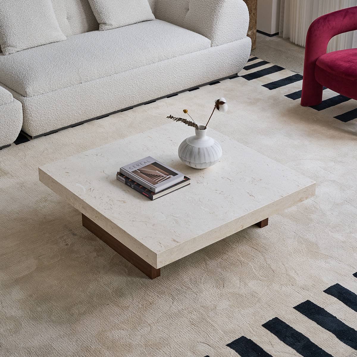 Wide shot of the B10 natural stone coffee table in a living room setting with a white sofa and striped rug.