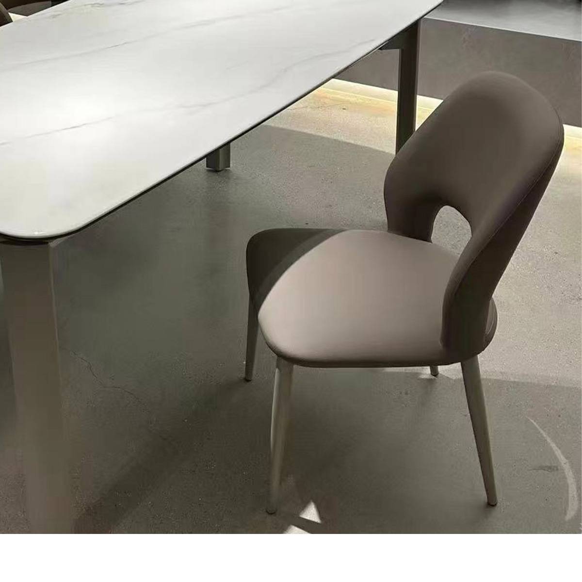 Grey modern dining chair placed next to a white marble dining table
