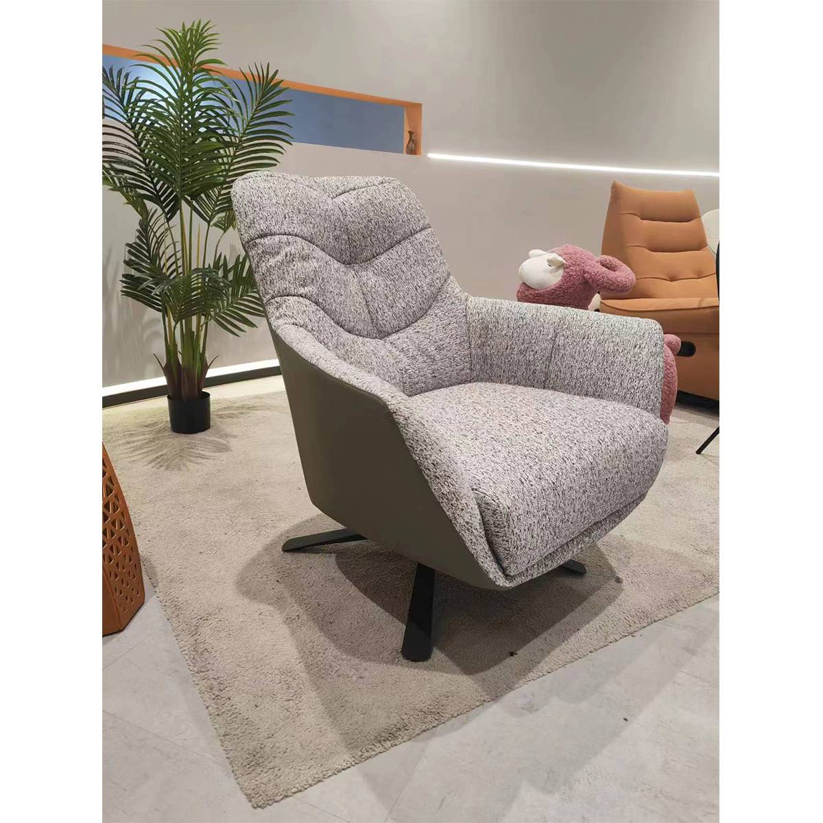 Side angle view of the lounge chair showing the curved armrests and swivel mechanism in a showroom setting.