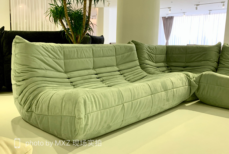 Green quilted velvet modular sofa section in a showroom setting