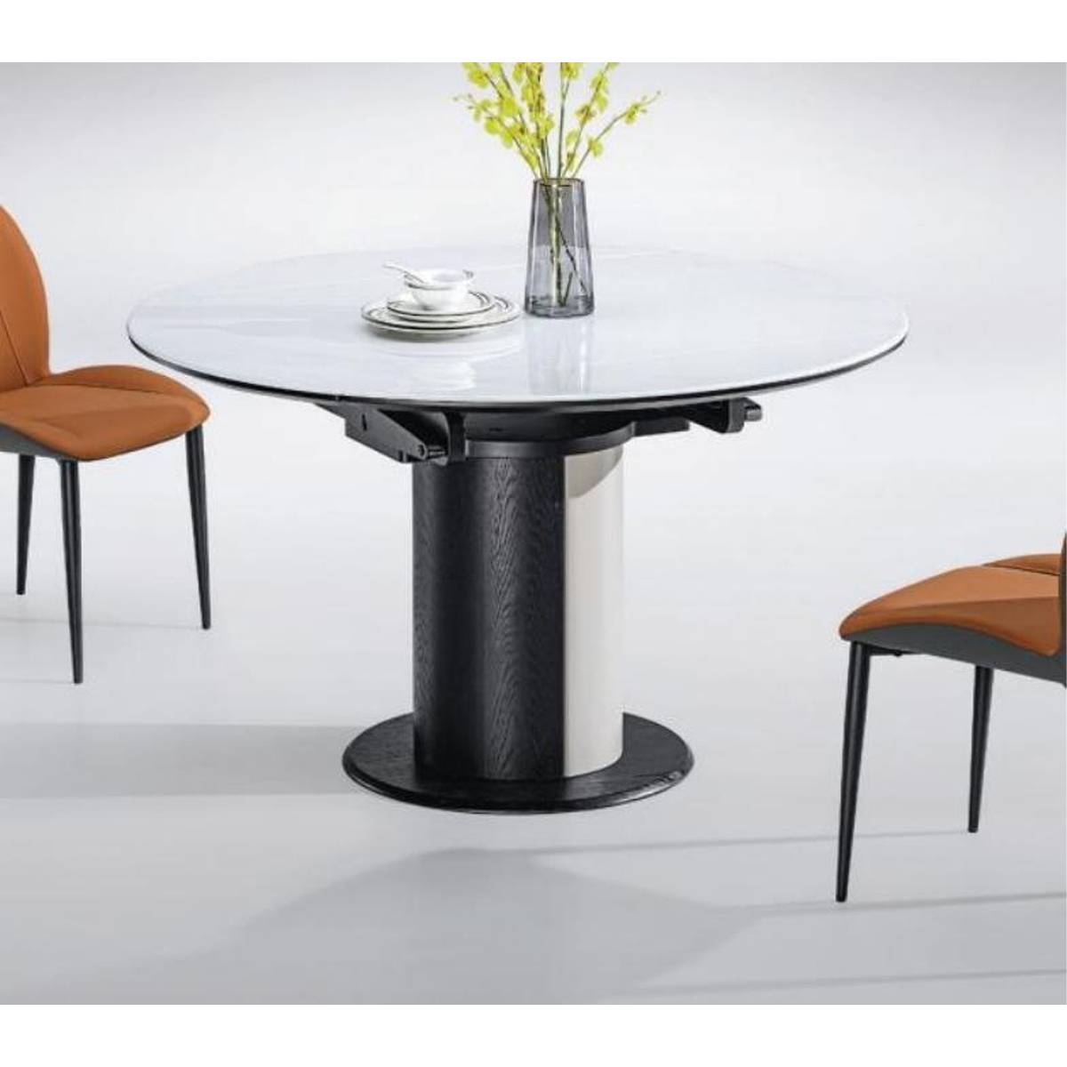 Full view of the round dining table set with a vase and plates, accompanied by orange dining chairs.