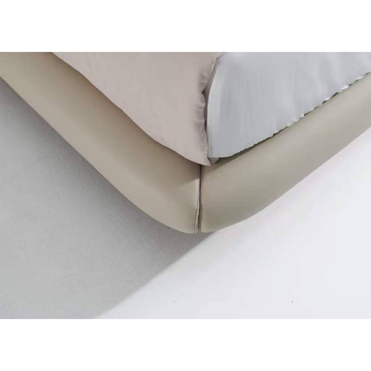 Close-up detail of the bed frame corner showing the leather stitching and metal leg