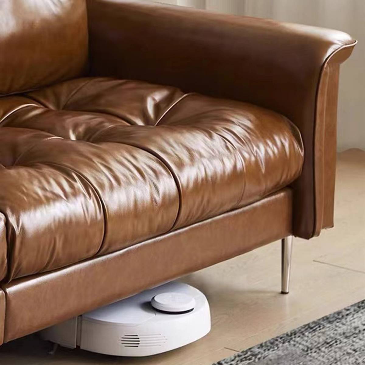 Close-up of the sofa base and chrome legs with a robot vacuum underneath