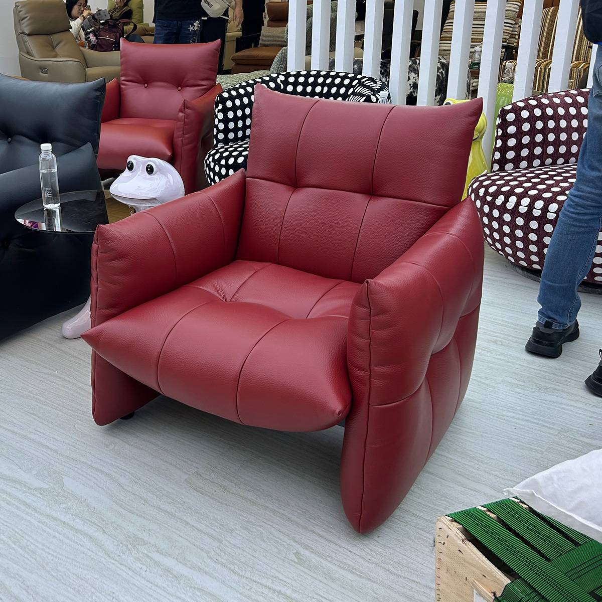 Red faux leather lounge chair with tufted back and seat, displayed in a furniture showroom