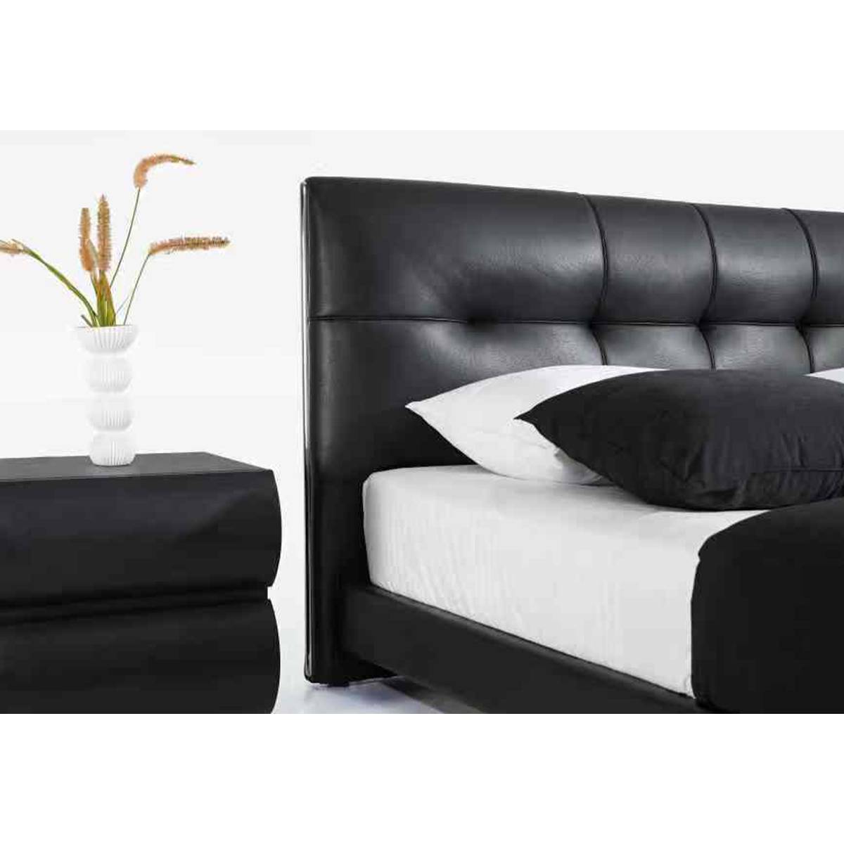 Side view of black leather bed with tufted headboard and matching bedside table