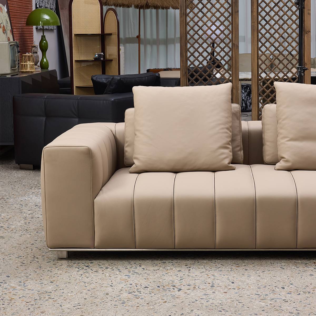Front view of beige leather sofa with segmented seat cushions and square pillows