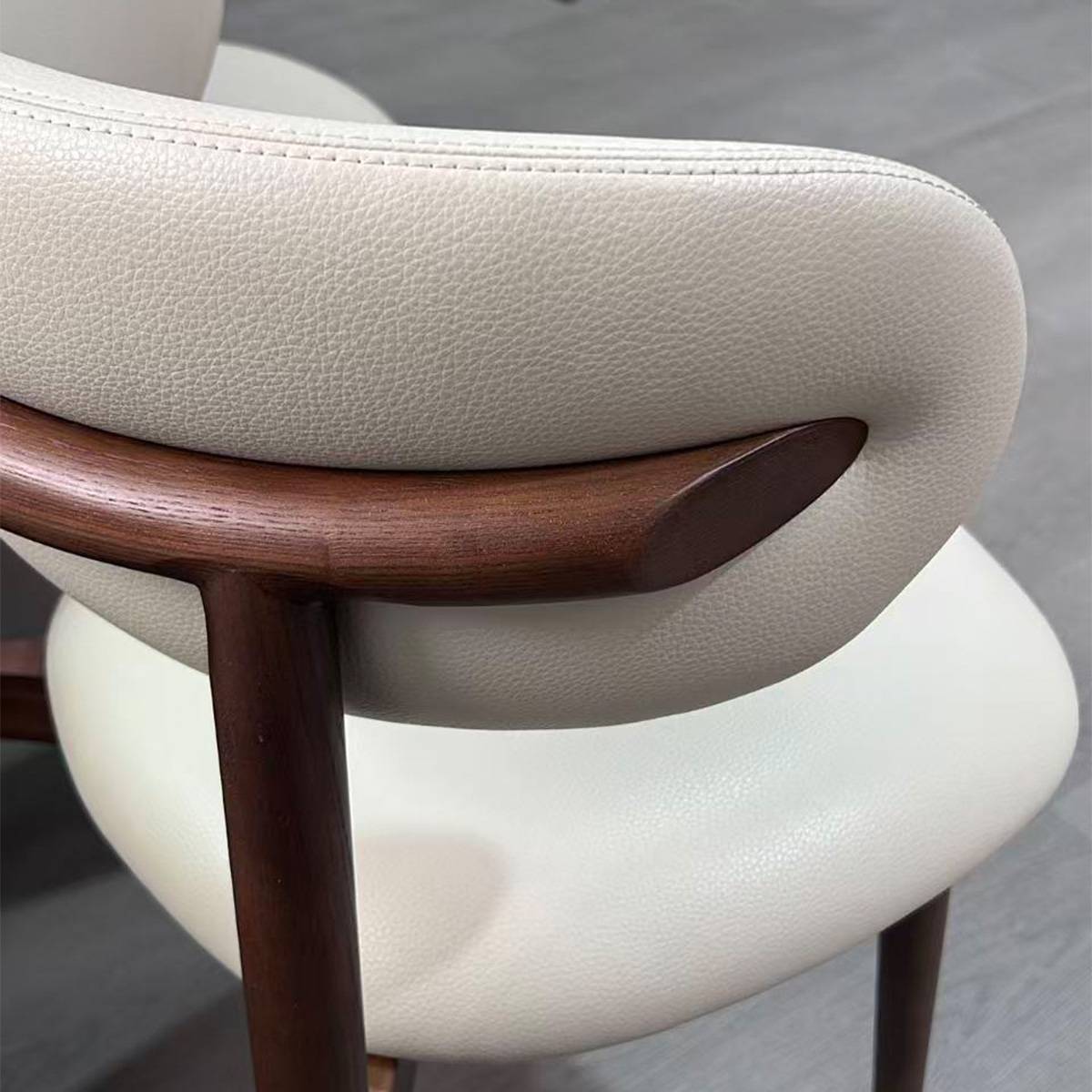 Close-up detail of the chair's backrest showing the PU leather texture and wood frame connection