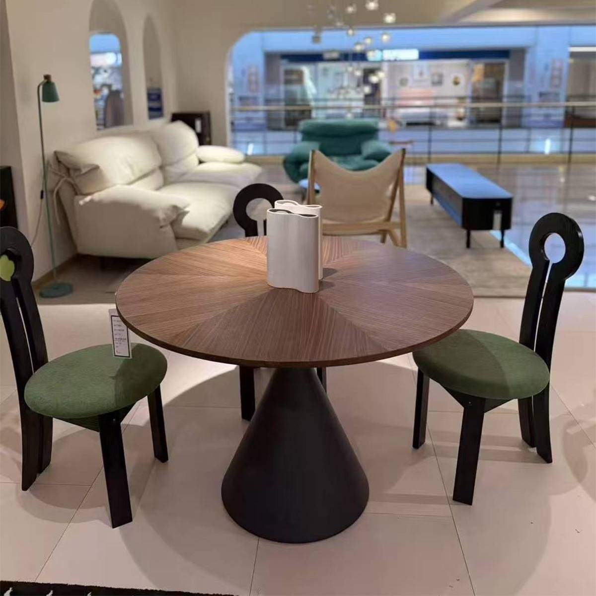 Dining table displayed in a showroom with green chairs