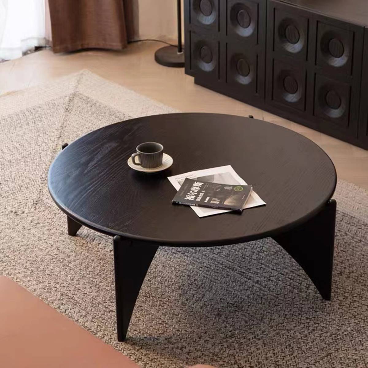 High angle view of black round coffee table with cup and magazine