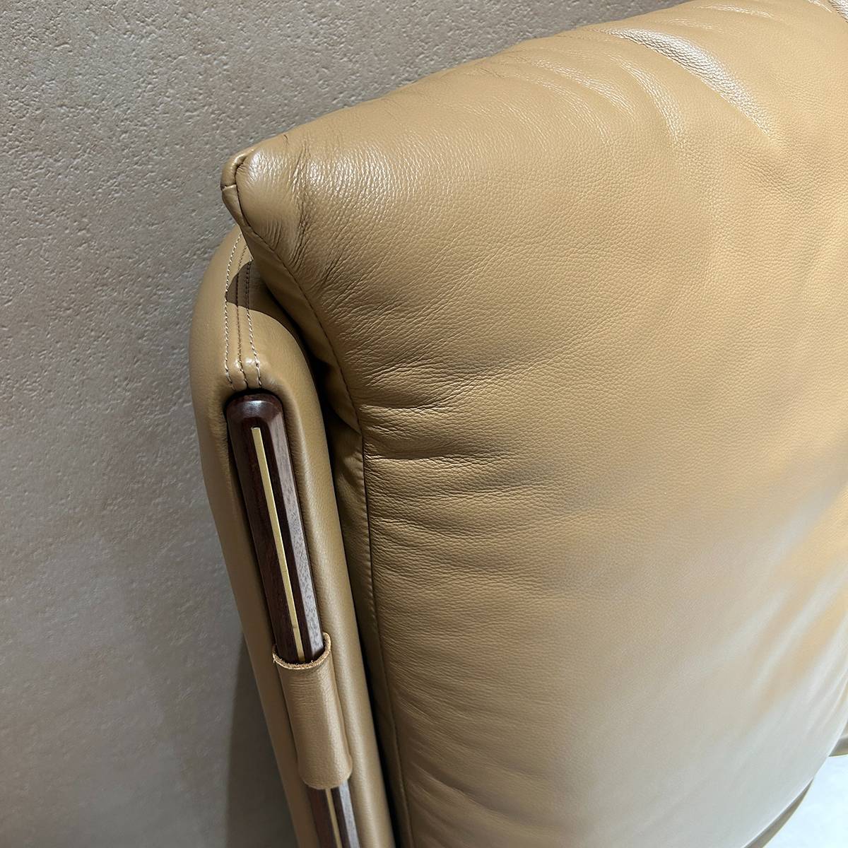 Close-up detail of the leather headboard stitching and wooden frame accent