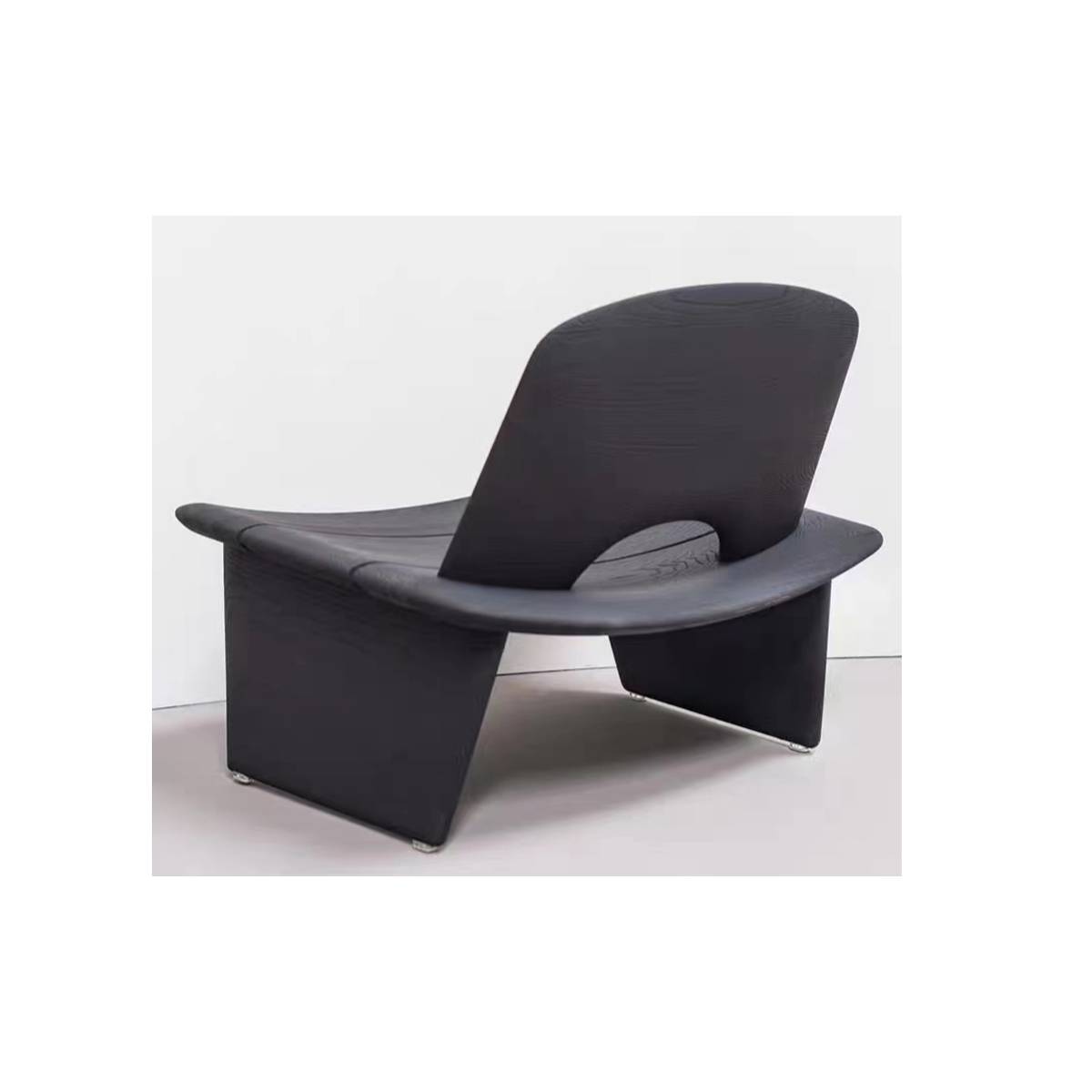 Side profile view of a black mid-century modern lounge chair with a curved backrest and solid wood base.