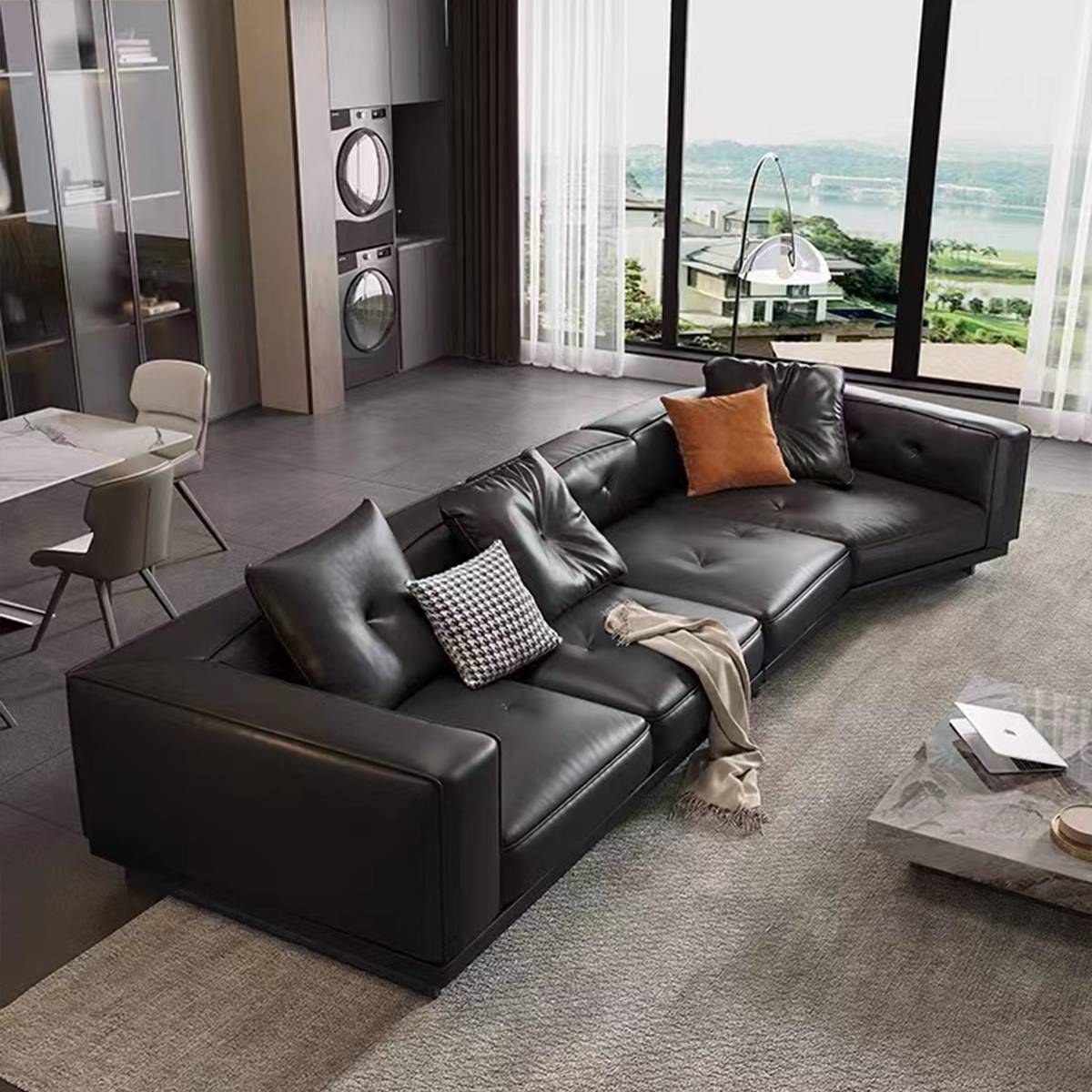 Black leather sofa in a modern living room with large windows and view