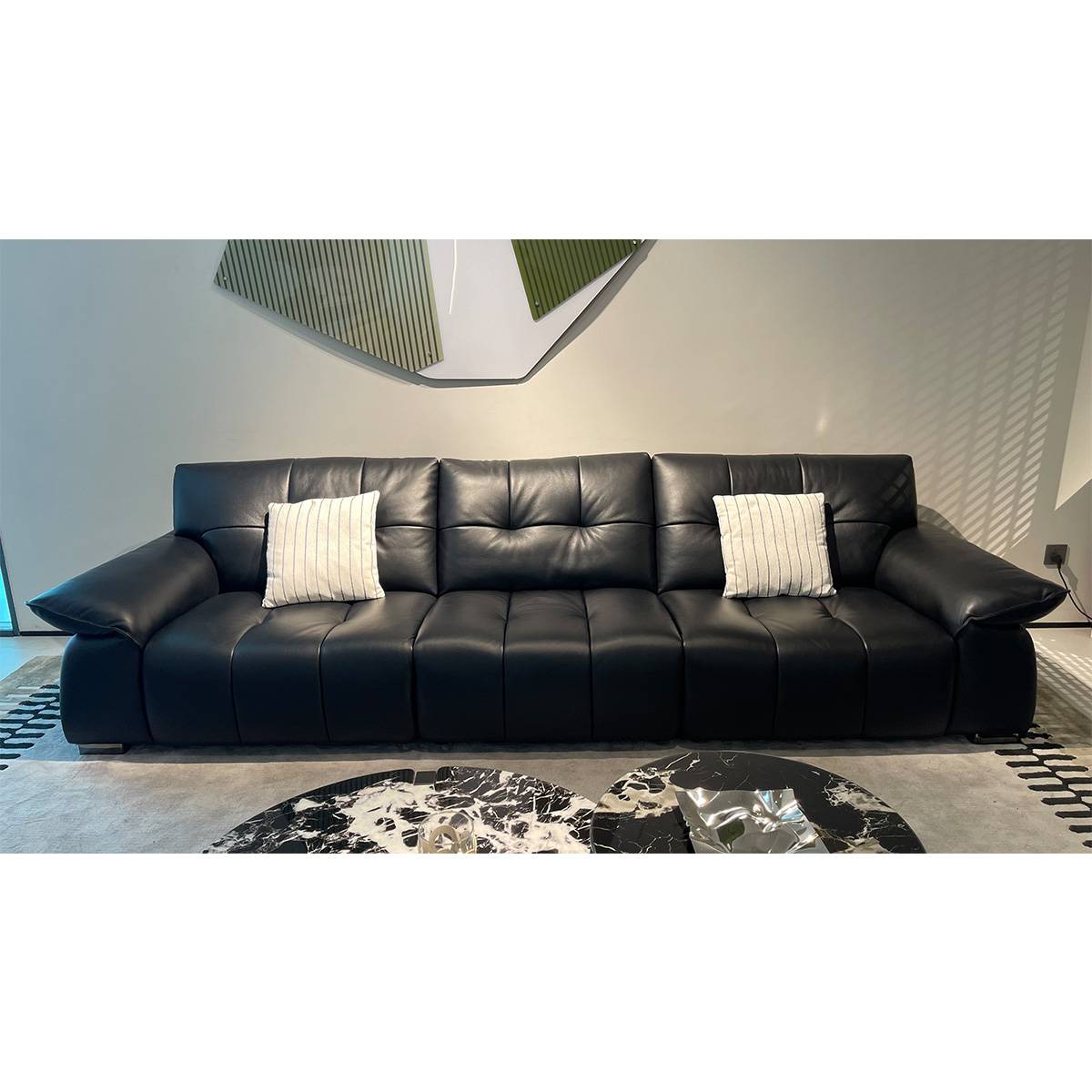 Black leather sofa in a modern living room setting with round coffee tables