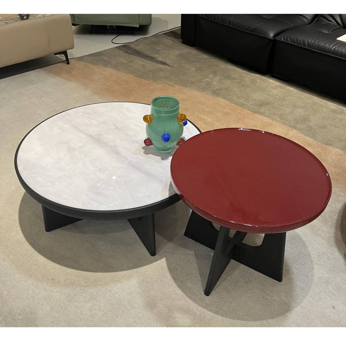 High-angle view of the white and red round coffee tables with a decorative vase on the white table.