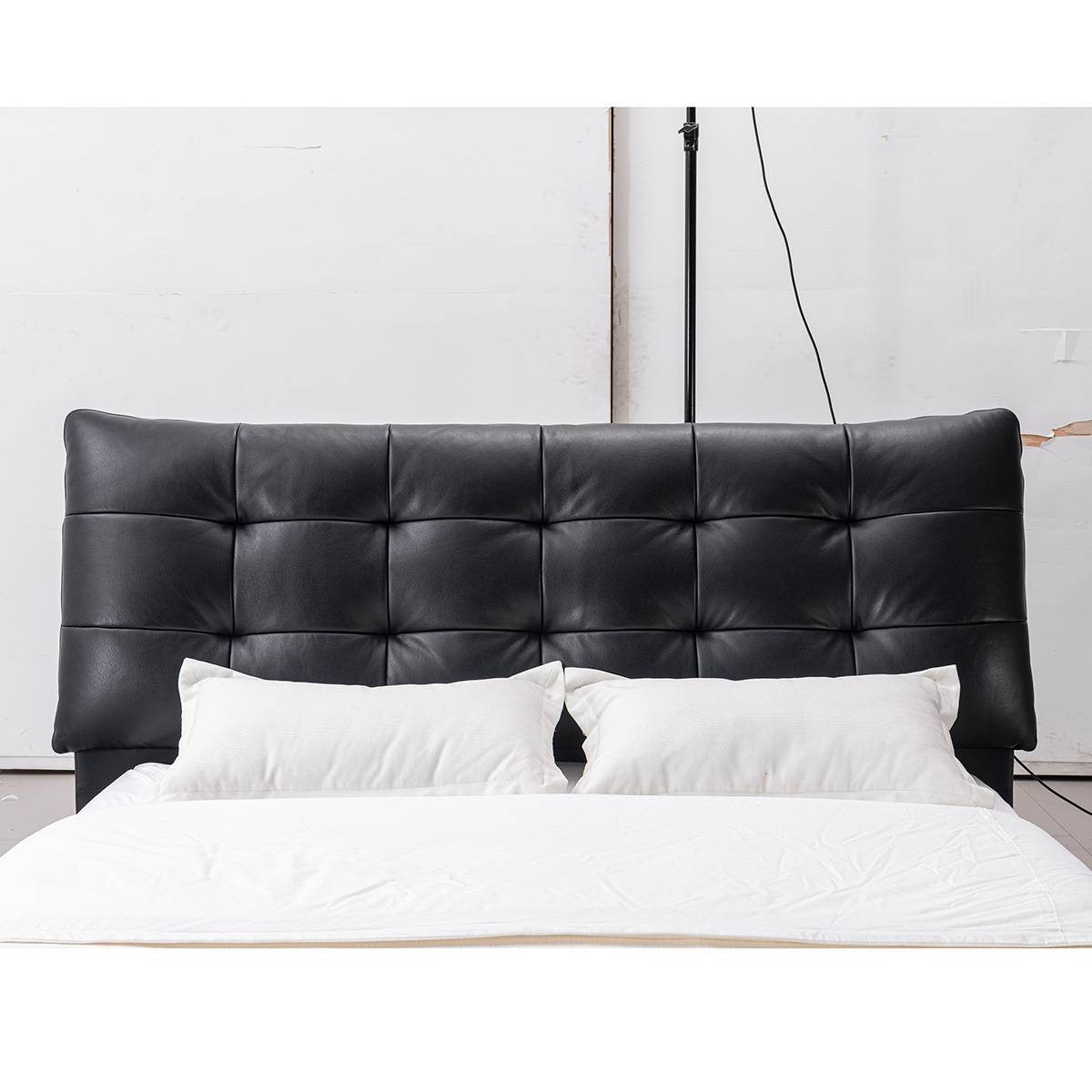 Front view of the black leather bed headboard with two white pillows
