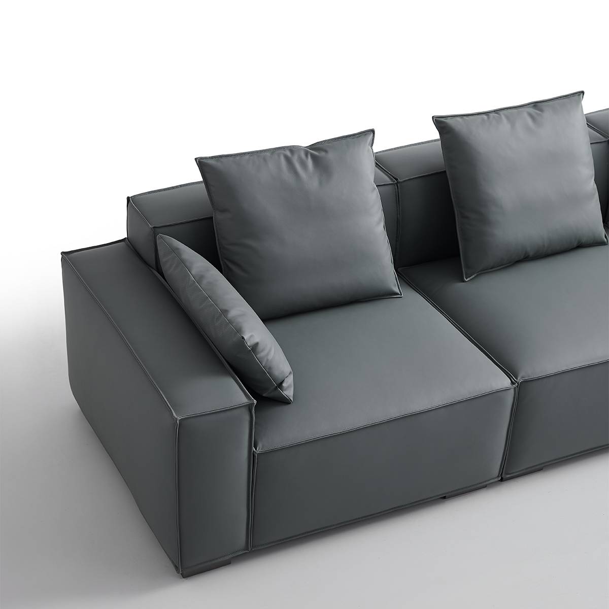 Side view of the grey modular sofa with square back cushions and a bolster pillow