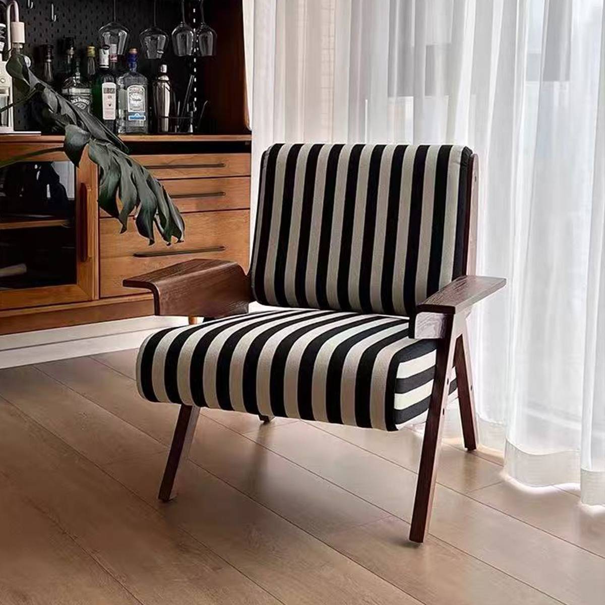 Lounge chair positioned near a window with sheer curtains