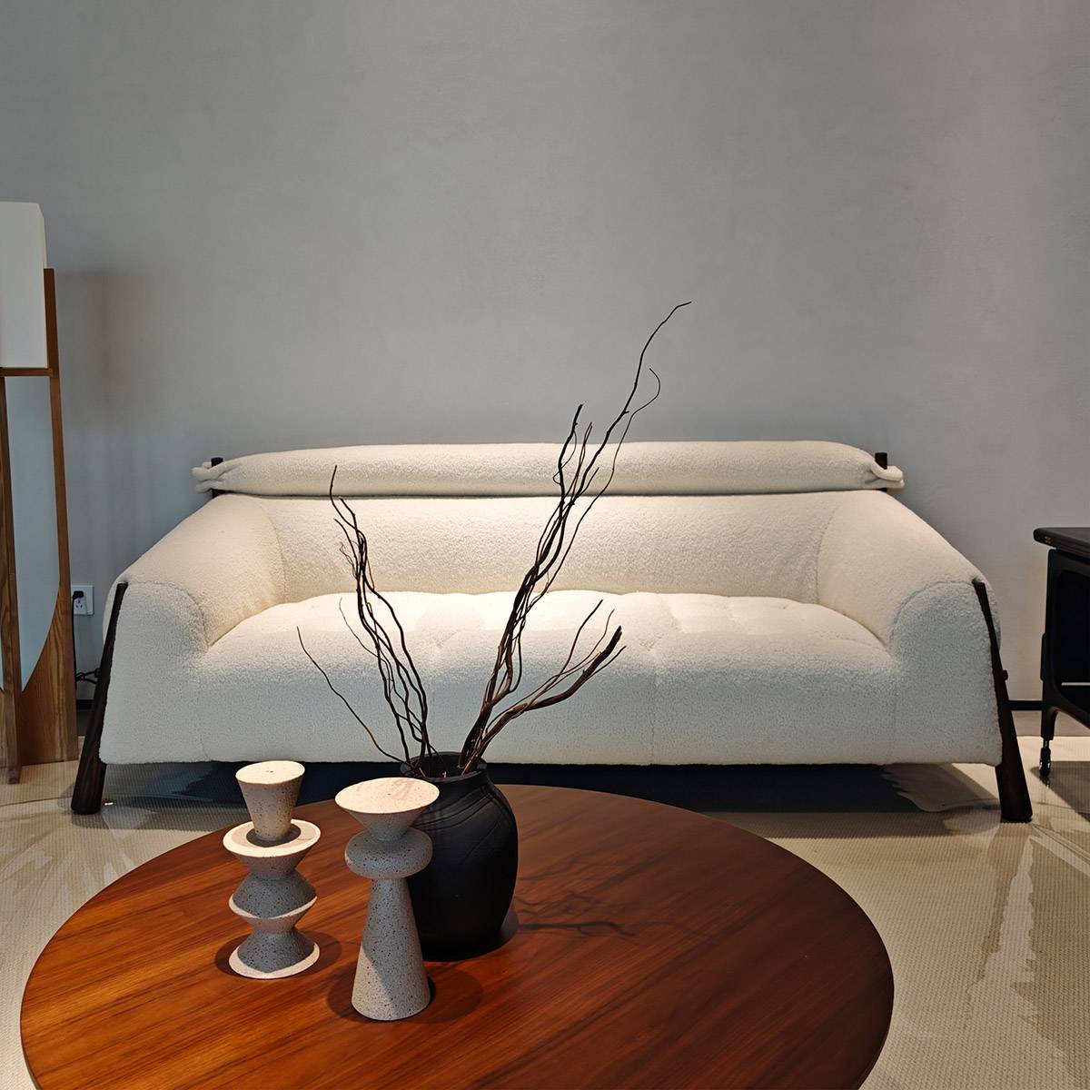 Close-up of the left side of the white bouclé sofa showing the wooden leg and armrest detail