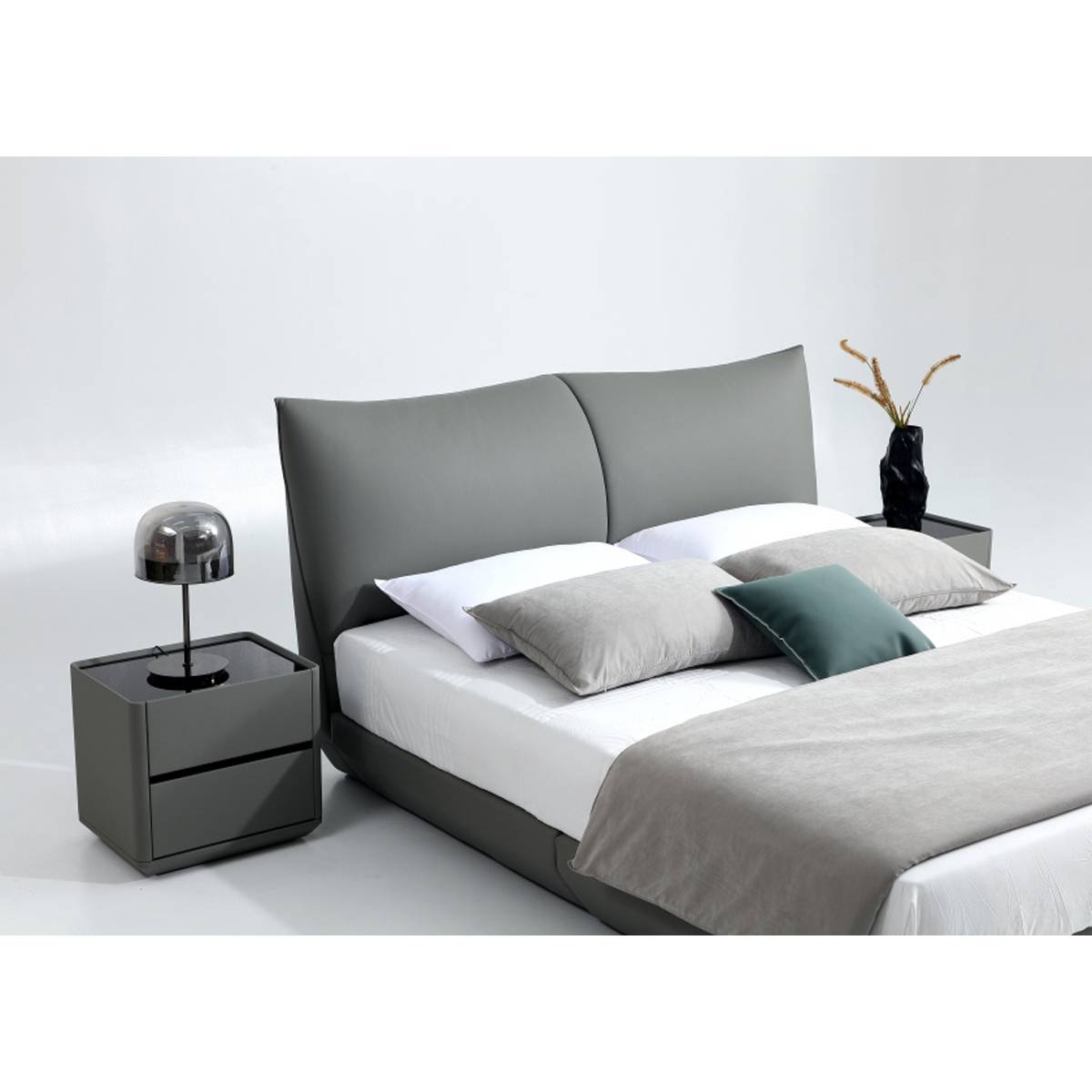 Full view of the grey upholstered bed with pillows and bedside table