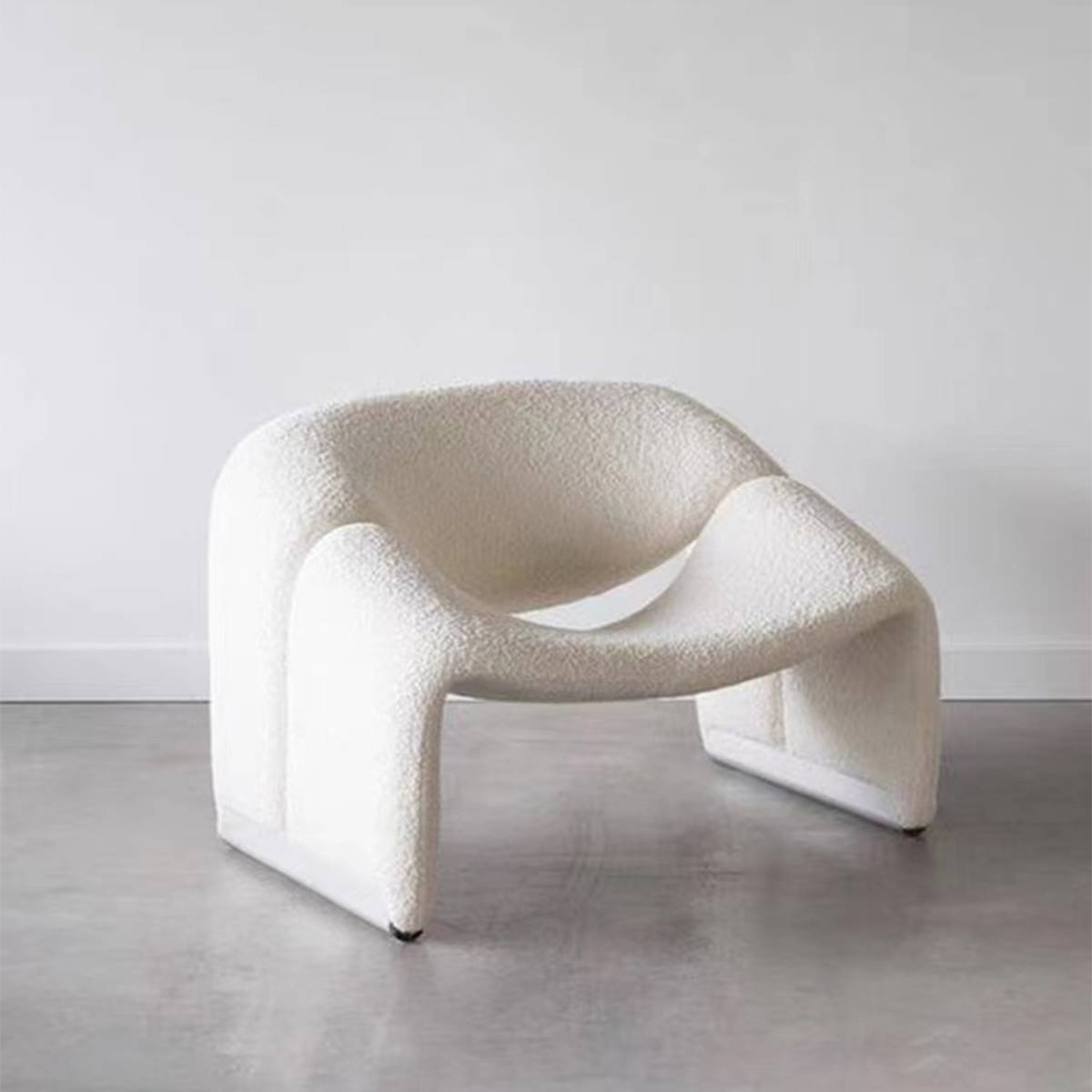 White bouclé lounge chair with curved design on a grey floor
