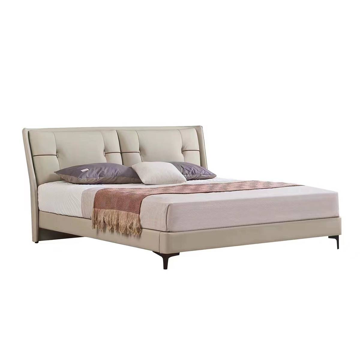 Side view of the beige tufted leather bed with pillows and throw blanket