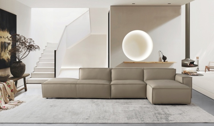 Lifestyle shot of the modular sofa arranged in an L-shape in a modern living room with a staircase and round wall light.
