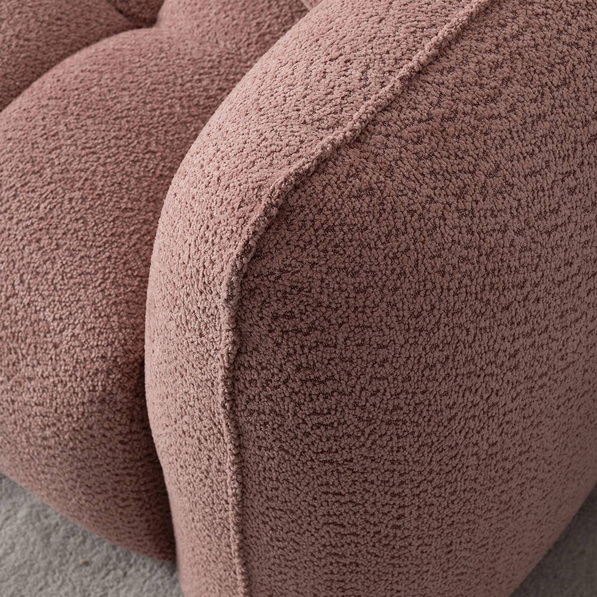 Close-up detail of the textured fabric and tufted stitching on the sofa arm