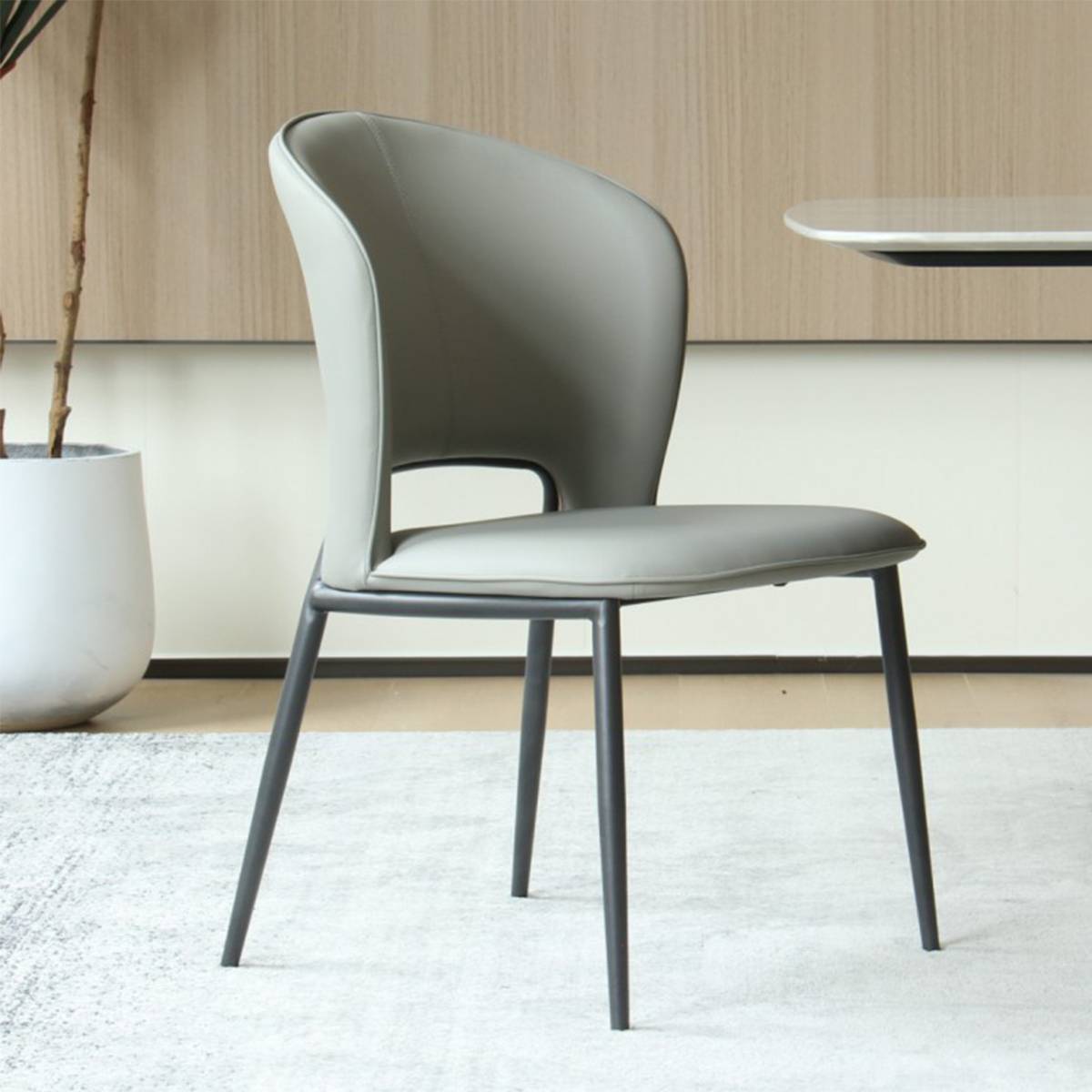 Side profile view of a beige grey modern dining chair next to a planter
