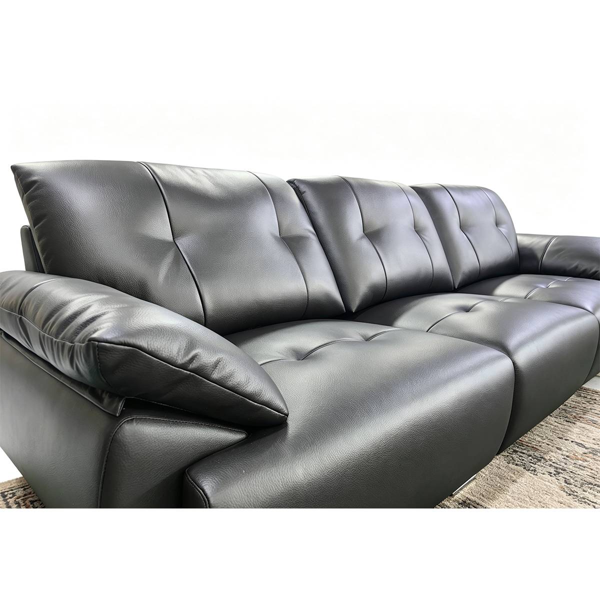 Close-up view of a black eco-leather straight sofa showing tufted seat cushions and backrest