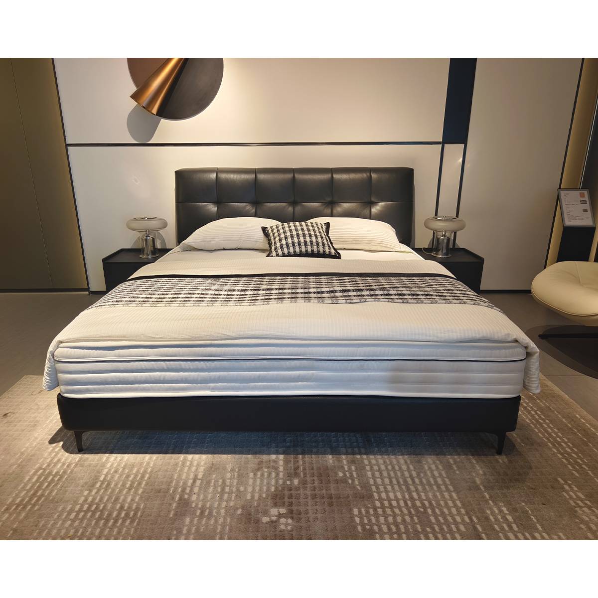 Angled view of the black leather bed frame in a modern bedroom setting.