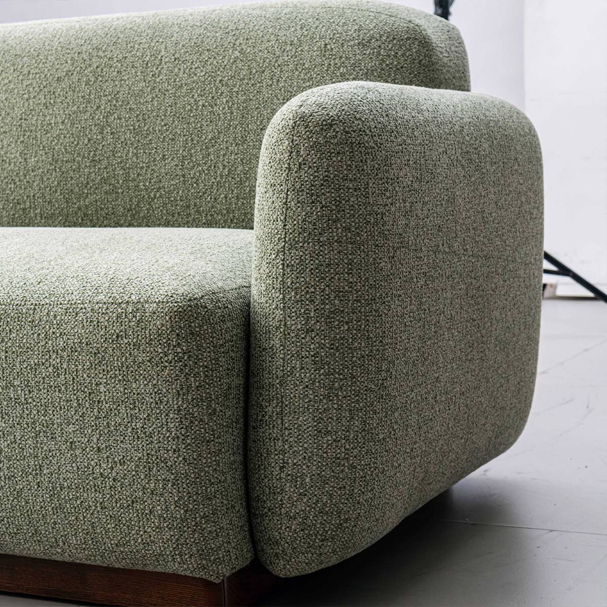 Close-up of the green fabric texture and armrest of the sofa