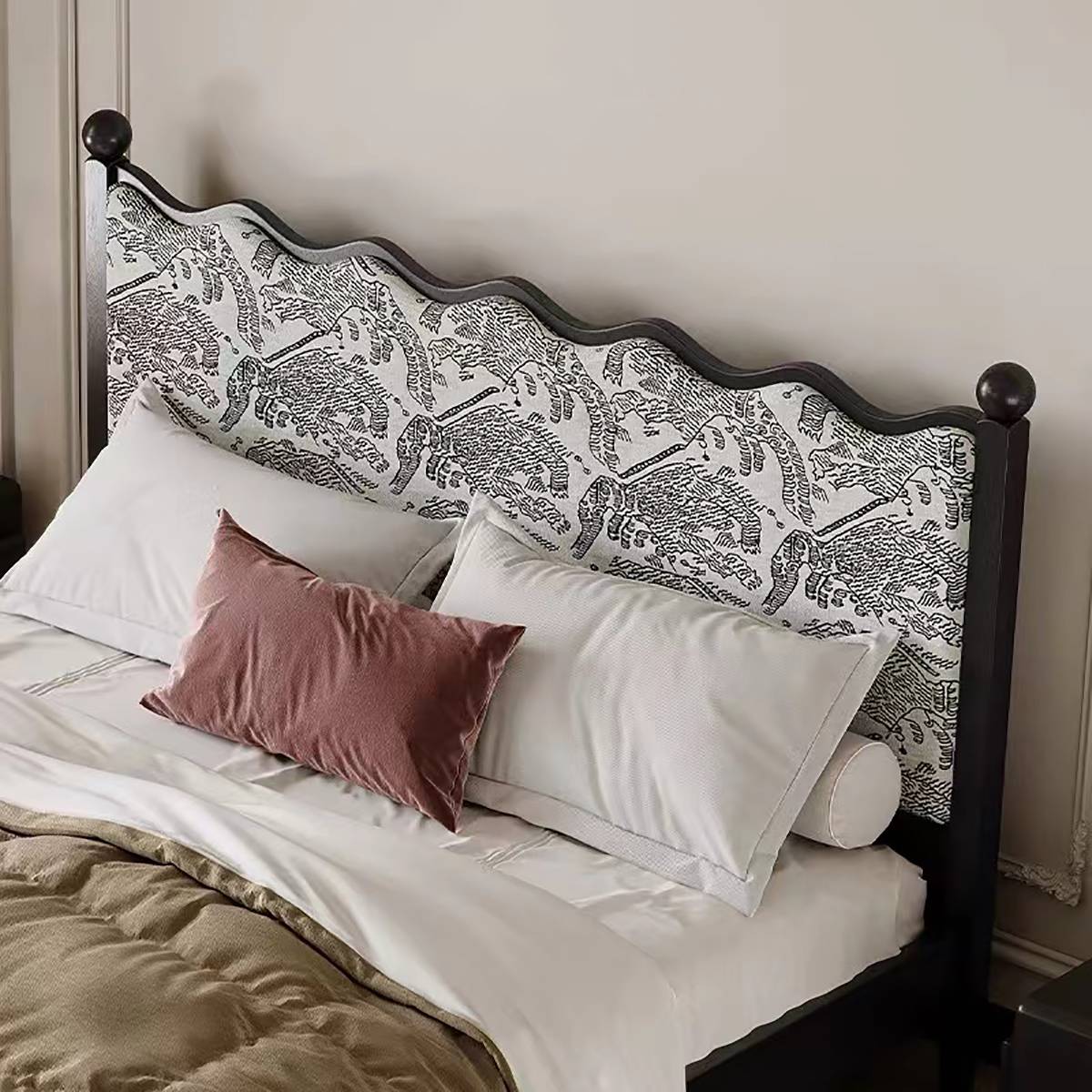 Close-up of the bed headboard showing the elephant pattern upholstery and pillows.