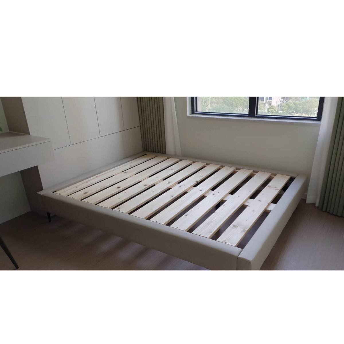 Light beige upholstered bed frame with wooden slats in a bedroom setting