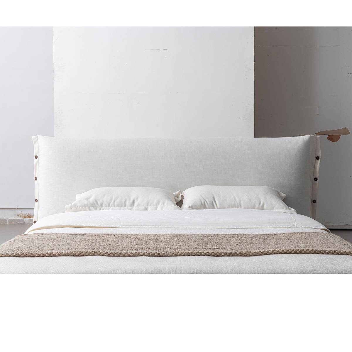 Front view of the upholstered bed with white bedding and a beige throw