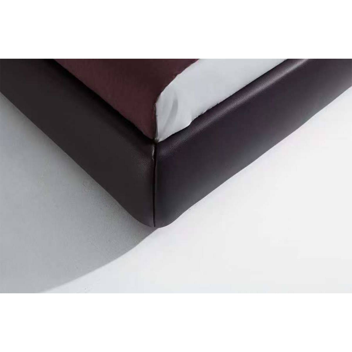 Close-up detail of the leather corner stitching and base of the bed frame