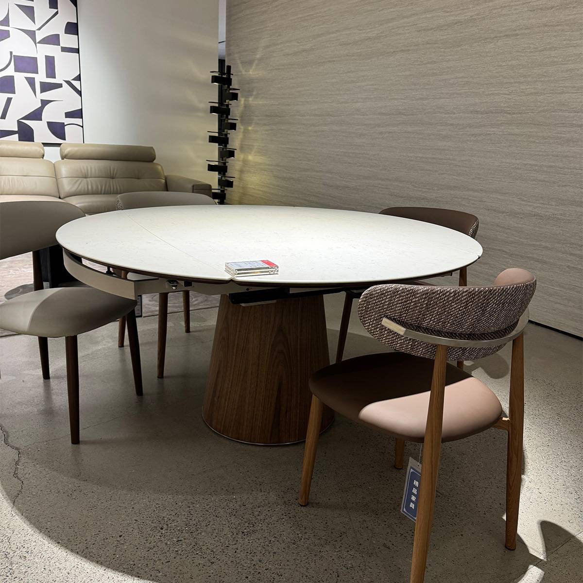 The dining table displayed in a showroom setting with chairs, showing the extension mechanism