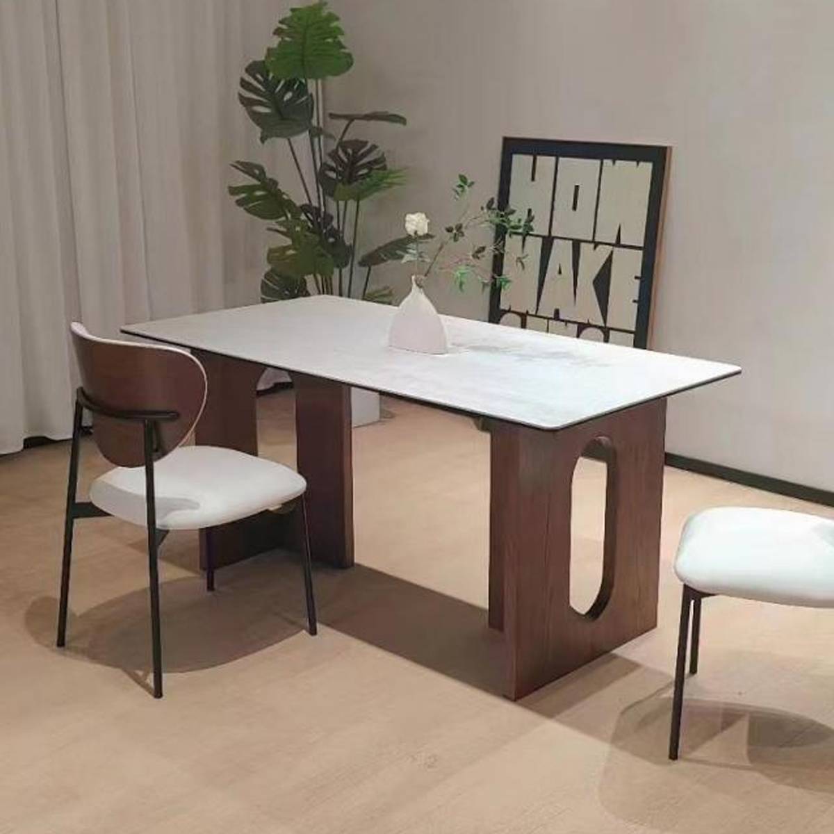 Dining table with white top and brown wood base in a minimalist setting