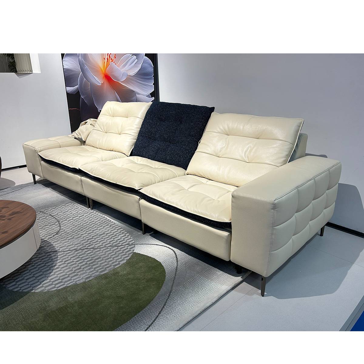 Angled view of the cream leather sofa with a dark throw pillow