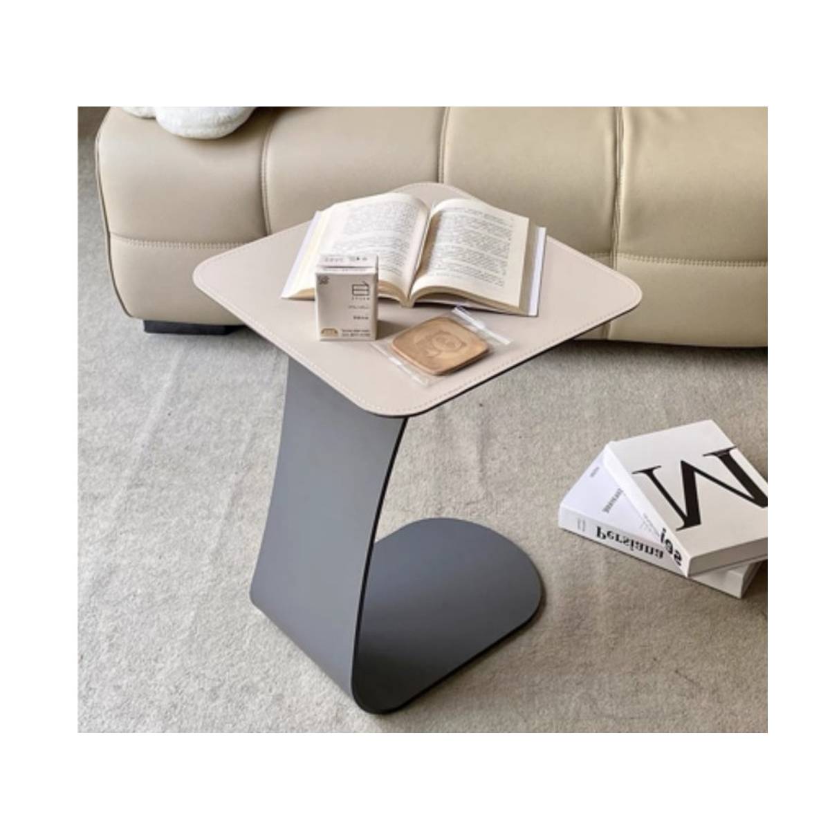 Beige saddle leather side table with curved metal base holding an open book