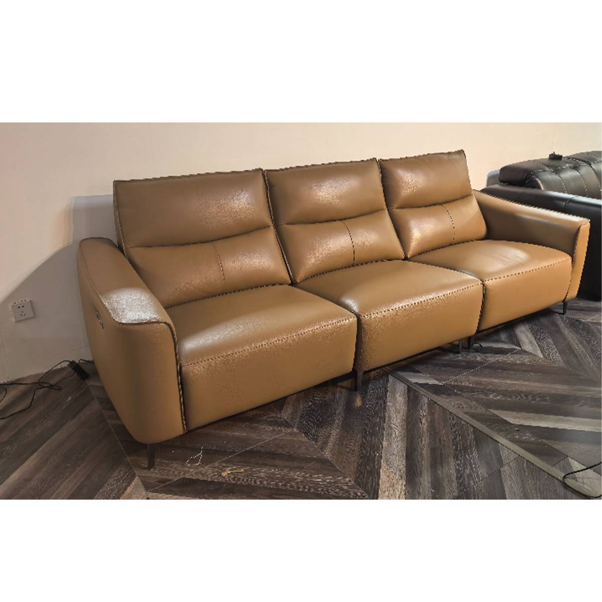 Close-up view of the tan leather sofa showing stitching details and reclining mechanism